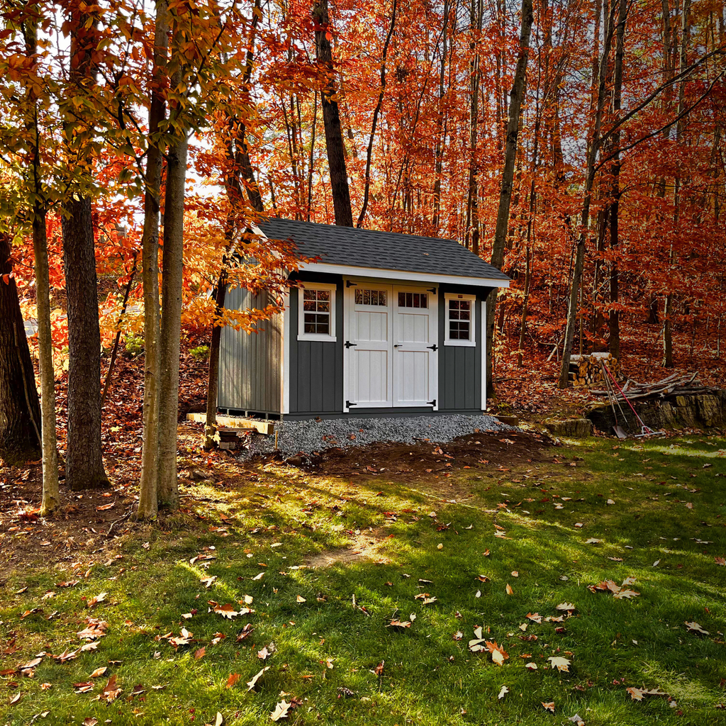 Small shed in a forest during autumn with colorful trees.